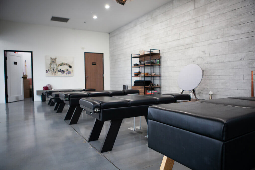The interior of a chiropractic adjustment clinic with three black adjustment tables and a clean appearance